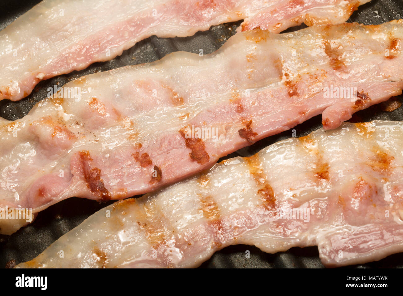 Streaky, unsmoked EU bacon from a supermarket fried on a George Foreman Fat Reducing Grill using the natural fat of the bacon. UK Stock Photo