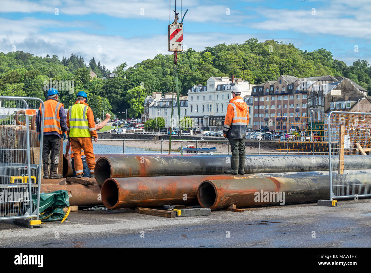 Construction site workers moving huge pipes in the harbour Stock Photo