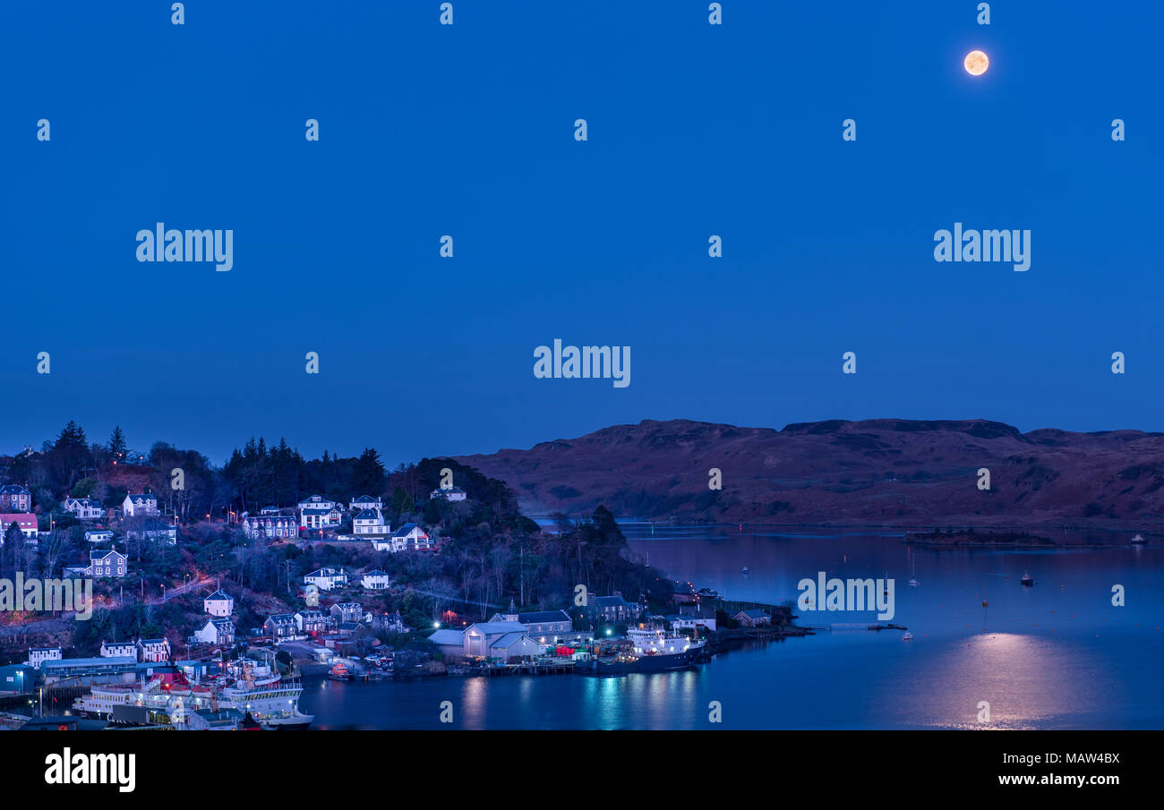 The Full Moon setting over the western islands of Scotland as the sun rises on Easter Sunday 1 April 2018. Viewed from McCaig's Tower in Oban Stock Photo