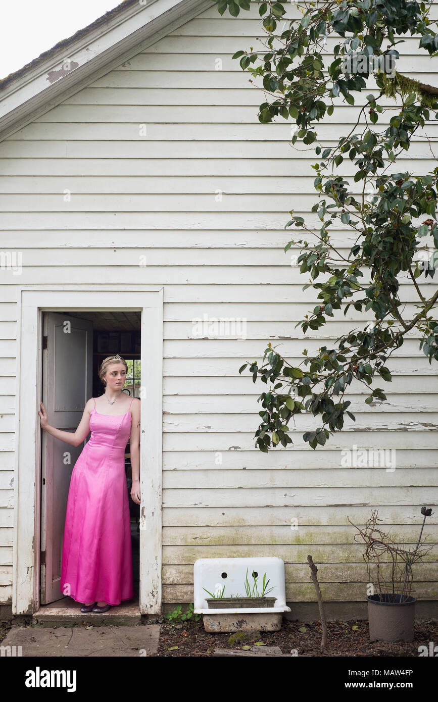 A young woman in her prom dress standing in a doorway. Stock Photo