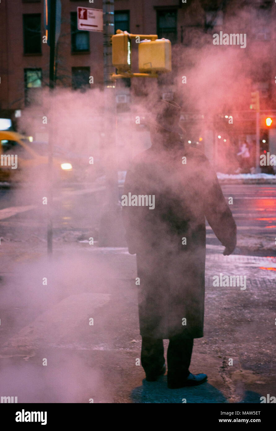 A man wearing a fedora standing on a steamy street in New York city. Stock Photo