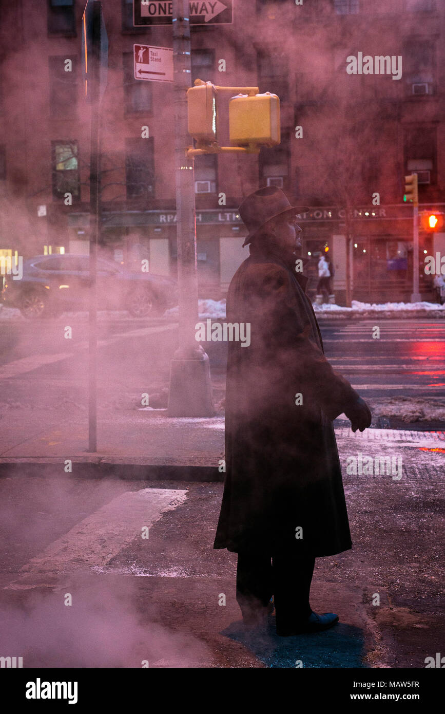 A man wearing a fedora standing on a steamy street in New York city. Stock Photo