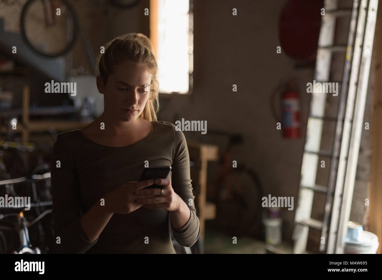 Female mechanic using mobile phone in workshop Stock Photo