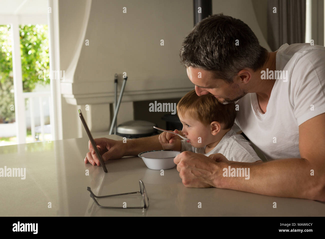 Father and son having breakfast while using digital tablet Stock Photo
