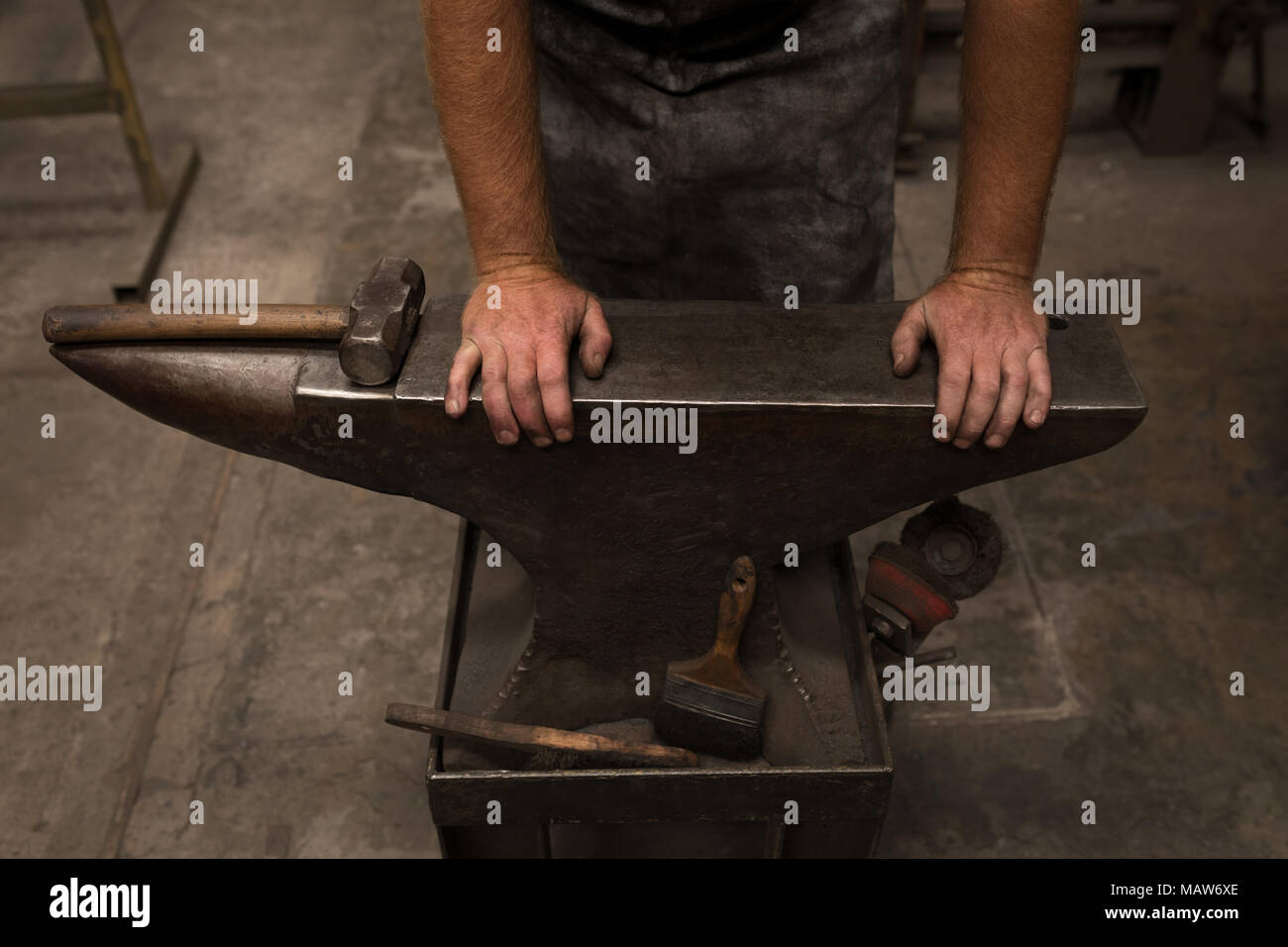 Blacksmith standing with hands on anvil Stock Photo