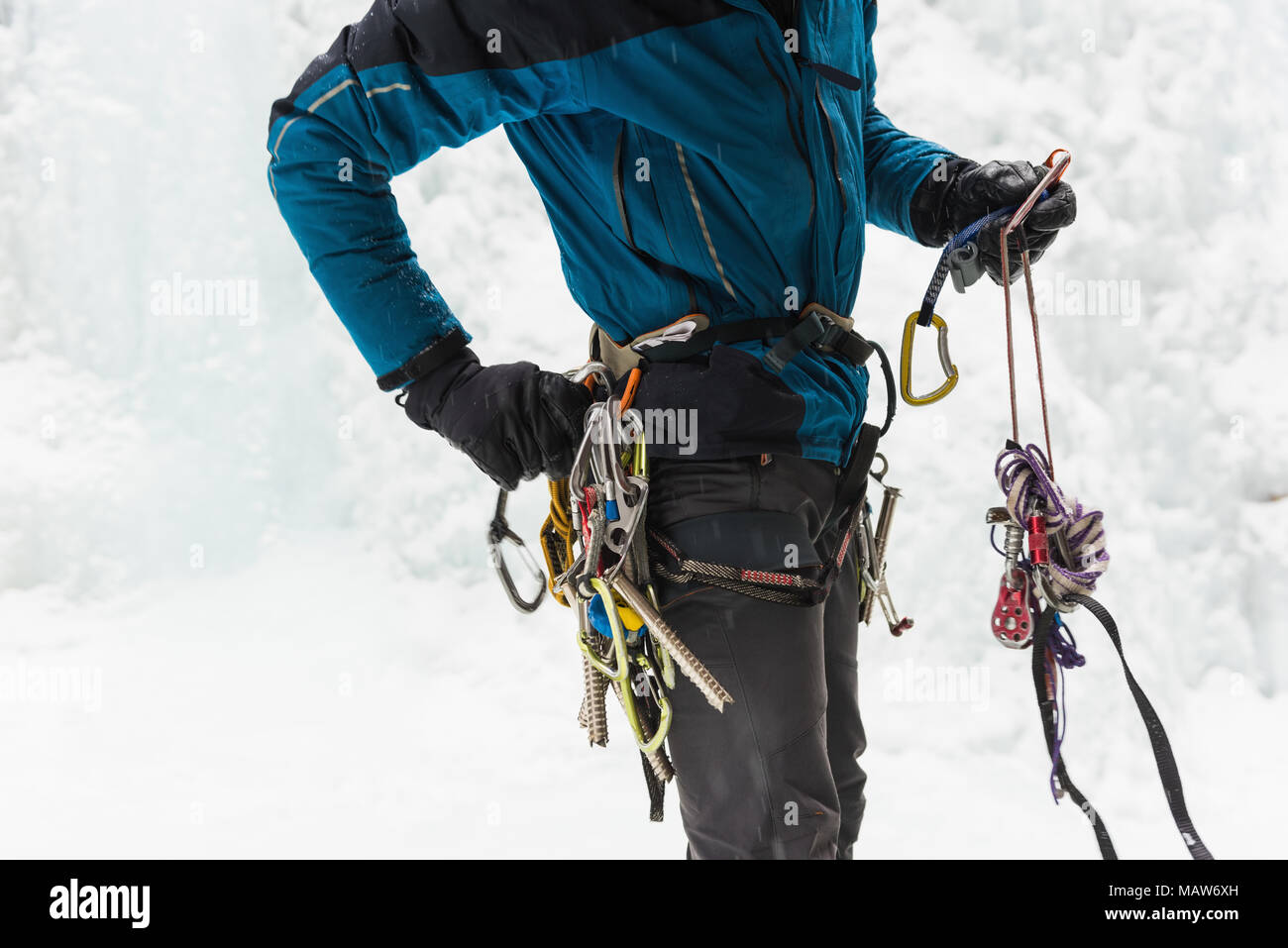 Male rock climber wearing harness near rocky mountain during winter Stock Photo