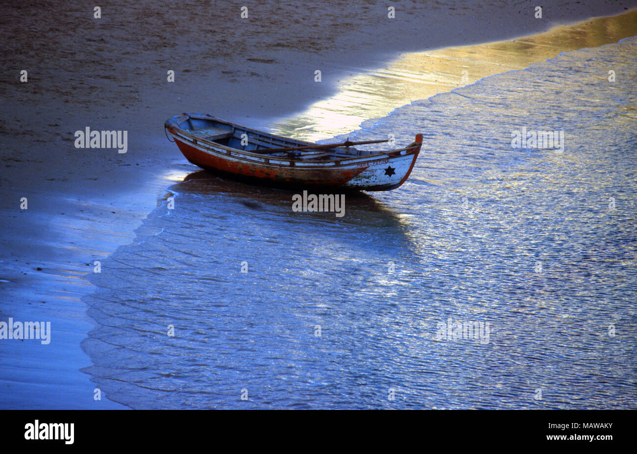 A rowboat sits at the water's edge in Estoril, Portugal Stock Photo