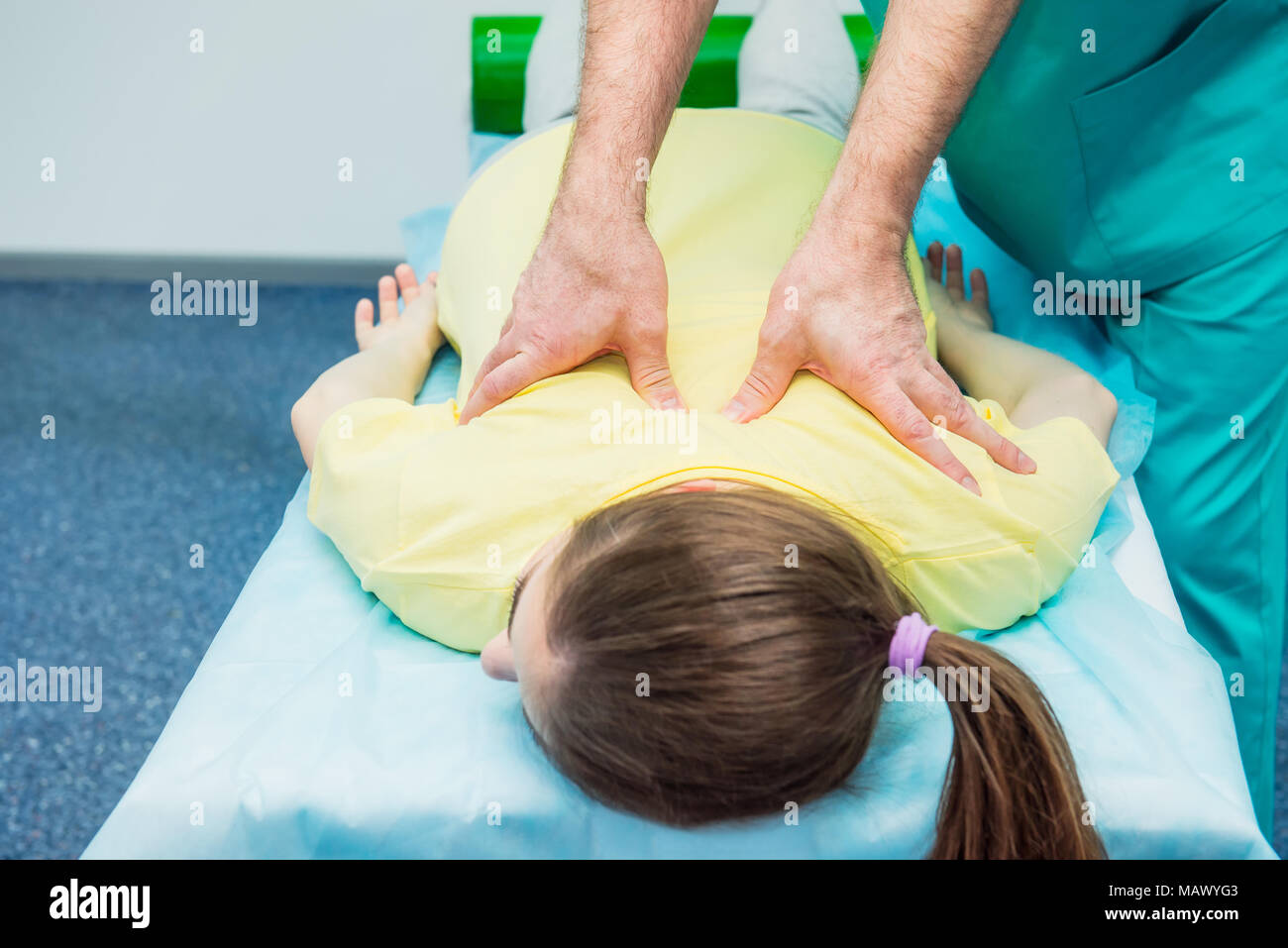 Young female receiving massage from therapist. A chiropractor stretching his patient's spine in medical office. Neurological physical examination. Ost Stock Photo