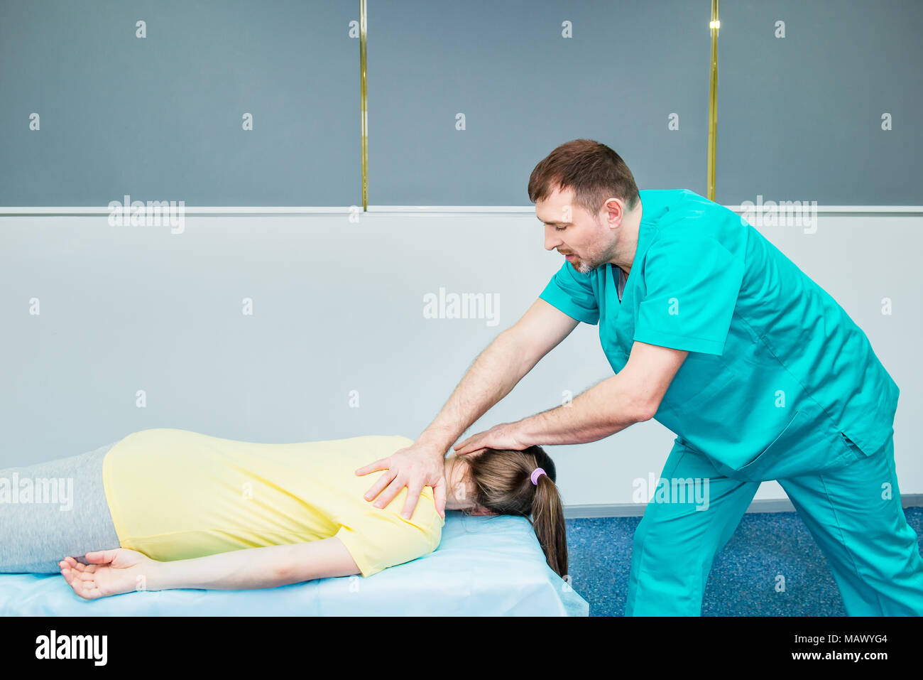 Young female receiving stretching osteopathy procedure in the neck from therapist in medical office. Neurological physical examination. Osteopathy, ch Stock Photo