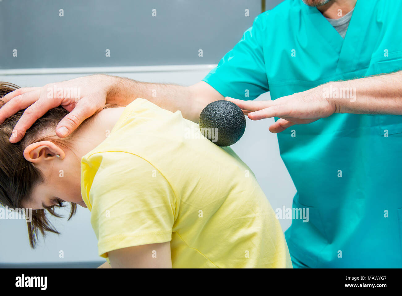 Woman at the physiotherapy receiving ball massage from therapist. A chiropractor treats patient's thoracic spine in medical office. Neurology, Osteopa Stock Photo