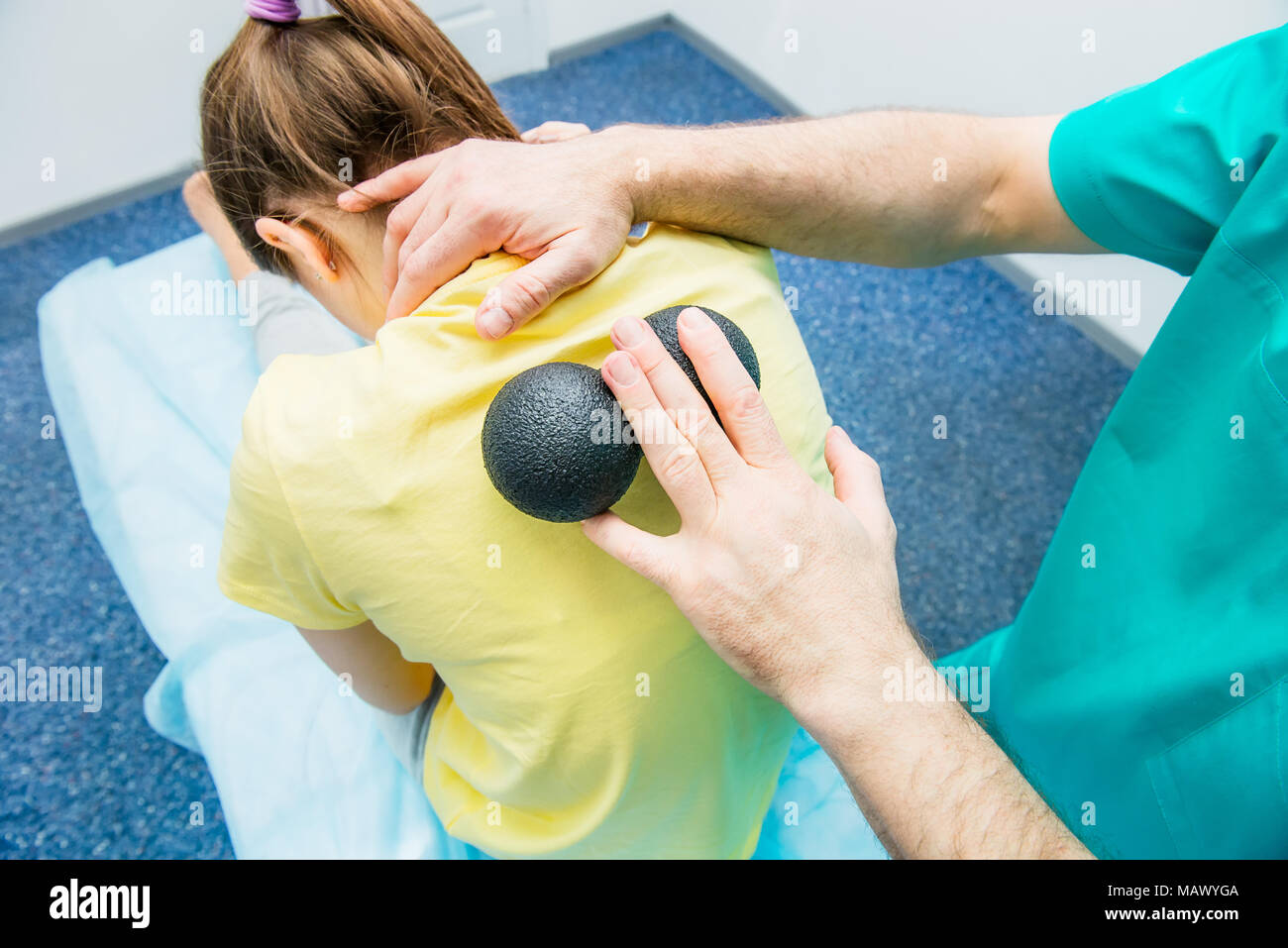 Woman at the physiotherapy receiving ball massage from therapist. A chiropractor treats patient's thoracic spine in medical office. Neurology, Osteopa Stock Photo