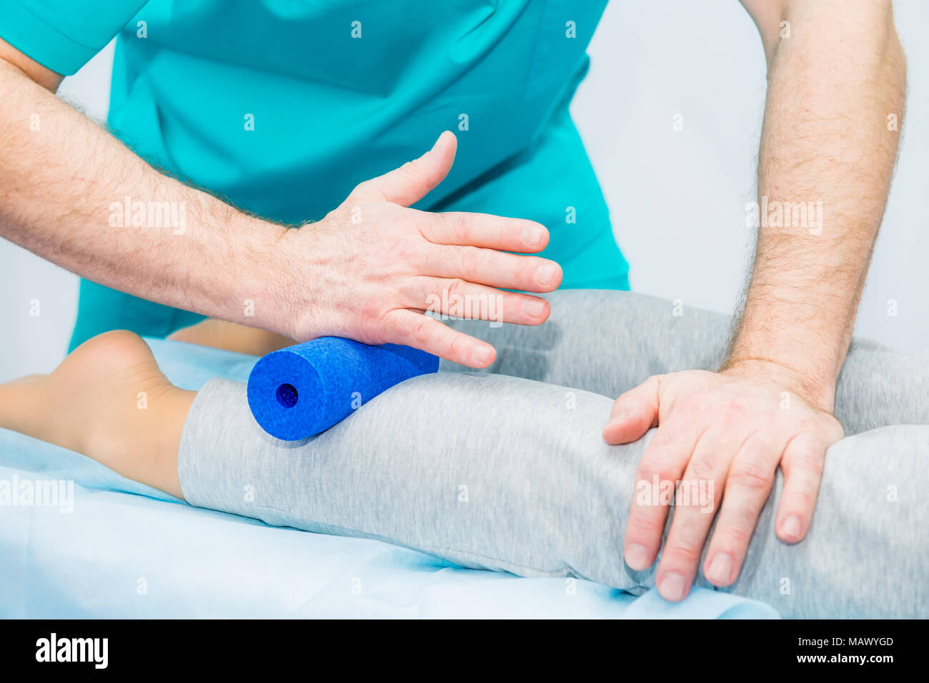Woman at the physiotherapy receiving roller massage from therapist. A chiropractor treats patient's leg, caviar in medical office. Neurology, Osteopat Stock Photo