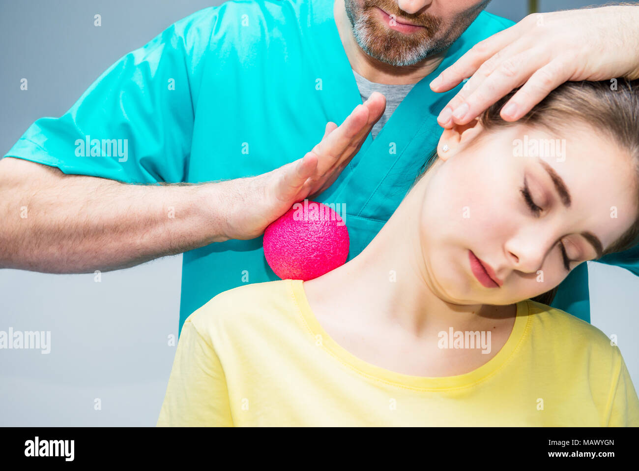 Woman at the physiotherapy receiving ball massage from therapist. A chiropractor treats patient's shoulder, neck in medical office. Neurology, Osteopa Stock Photo