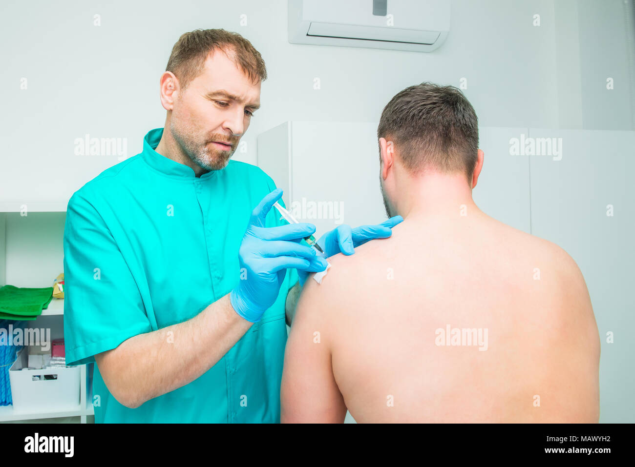Neurologist doctor makes an injection therapy, blockade into deltoid muscle of male patient. Alternative pain treatment concept. Selective focus, spac Stock Photo