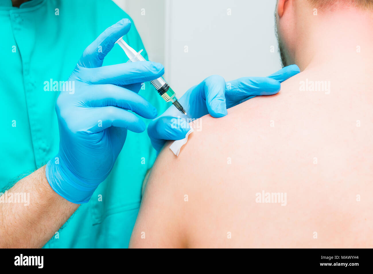 Close up Neurologist doctor makes an injection therapy, blockade into deltoid muscle of male patient. Alternative pain treatment concept. Selective fo Stock Photo