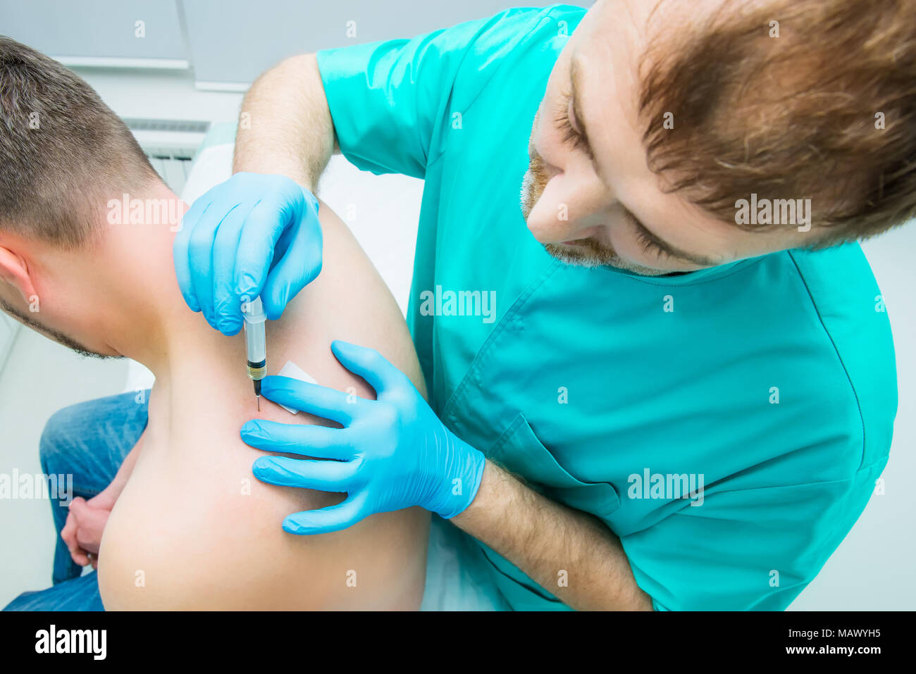 Neurologist doctor makes an injection therapy, blockade into trapezium muscle of male patient. Alternative pain treatment concept. Selective focus, to Stock Photo