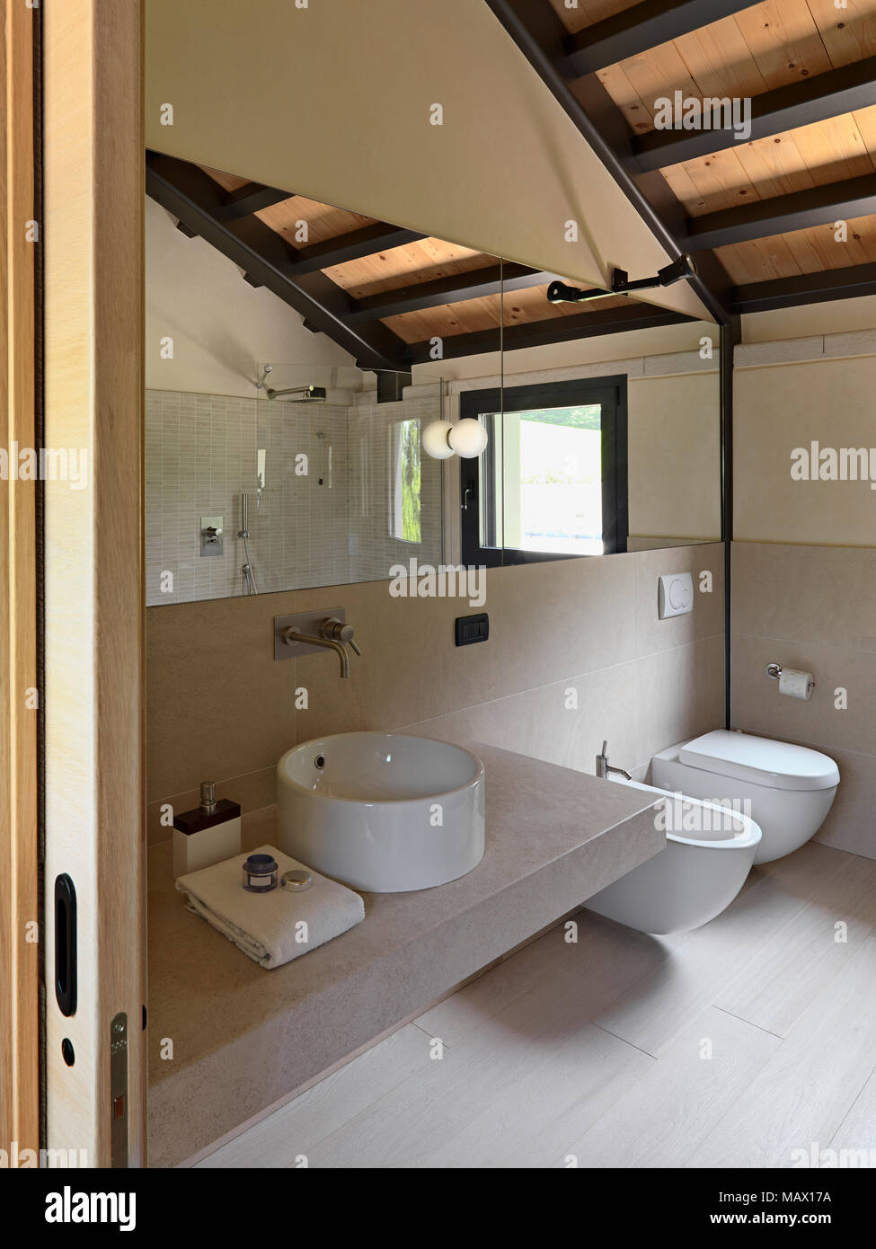 interiors hosts of a modern bathroom, in the foreground round counter top washbasin on hte marble top in background the bidet and the toilet bowl the  Stock Photo