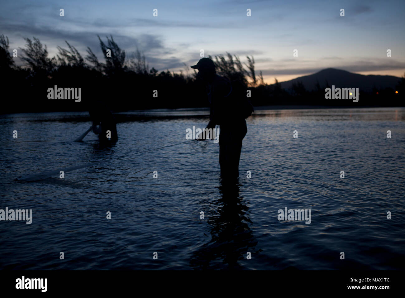A fisherman spreads fishing net to catch river prawns in a sunset Local: Garopaba/SC Autor: E Stock Photo