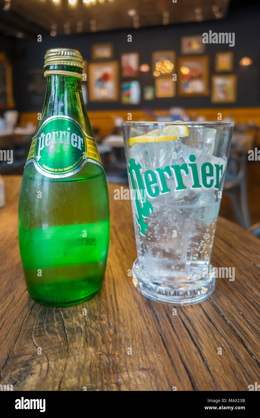 A glass and a bottle of cold Sparkling Perrier mineral water in a French style café Stock Photo