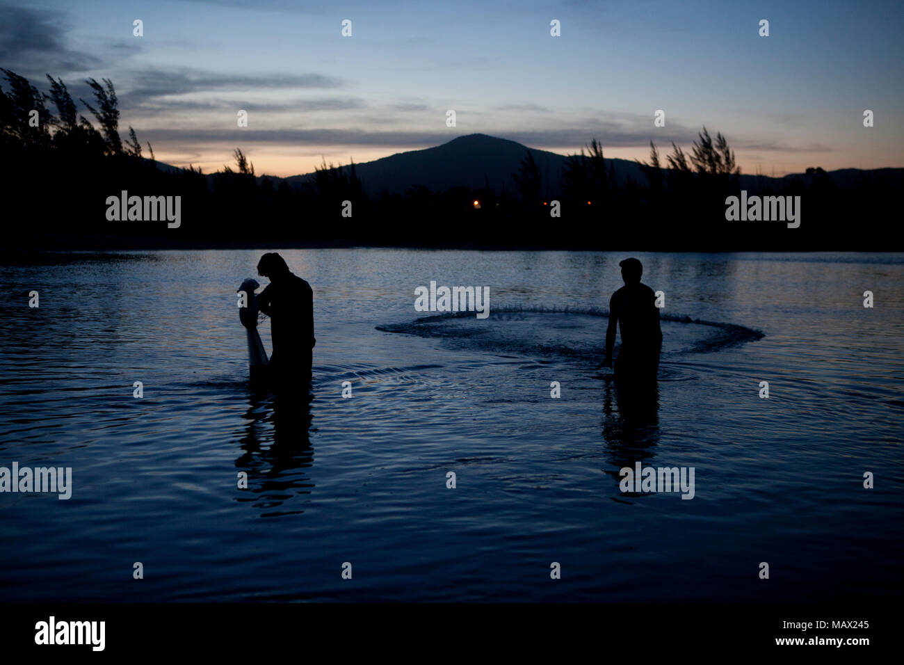 A fisherman spreads fishing net to catch river prawns in a sunset Local: Garopaba/SC Autor: E Stock Photo