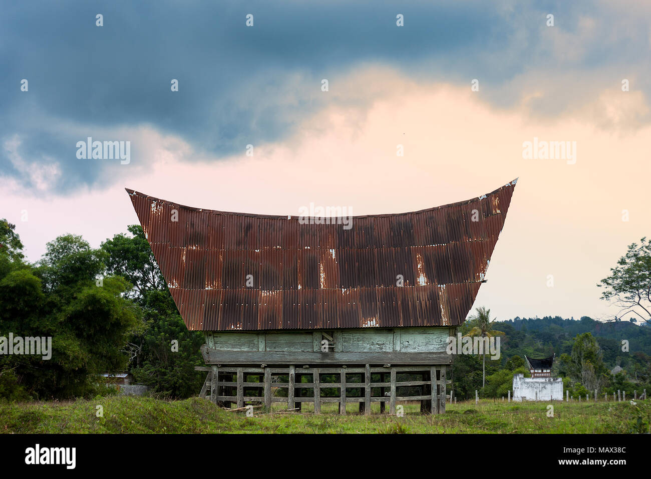 An old traditional Batak architecture styled farm storage barm  with wood frame and carvings sits raised in a farmers field. Lake Toba, Sumatra, Indon Stock Photo