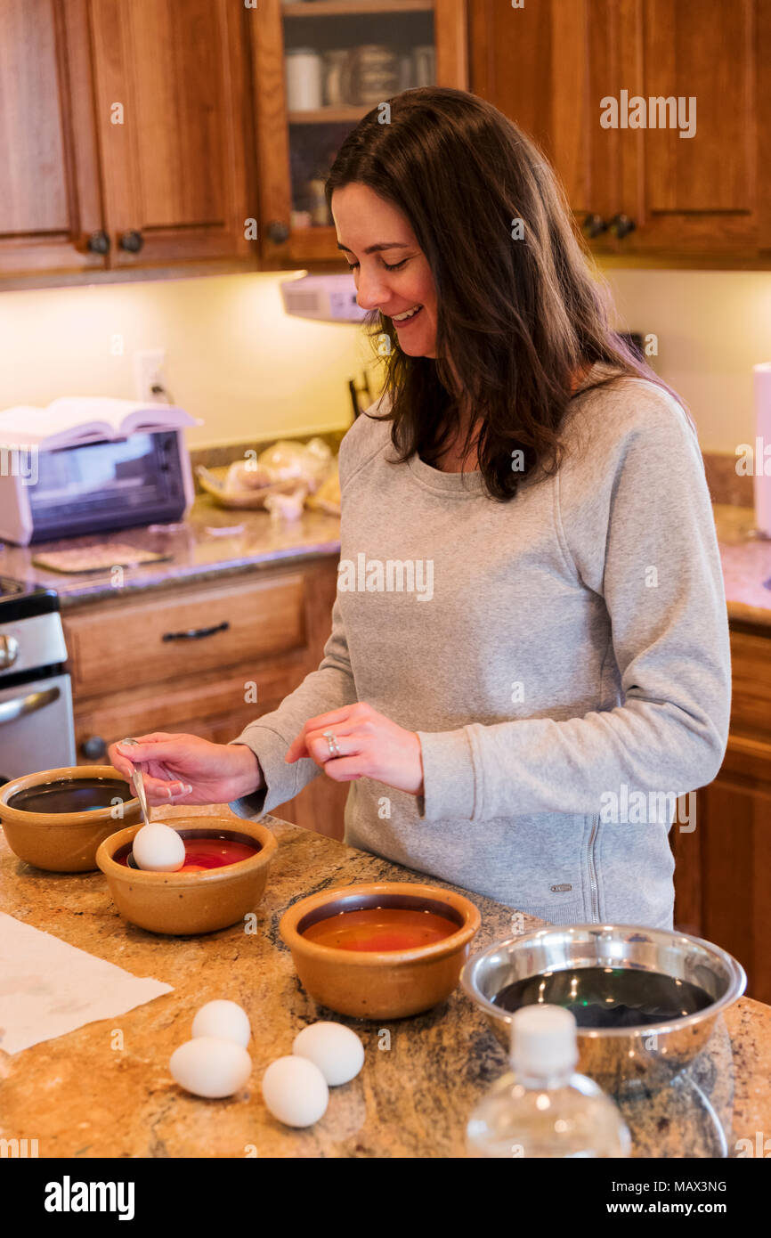 Woman dyeing Easter eggs in kitchen Stock Photo