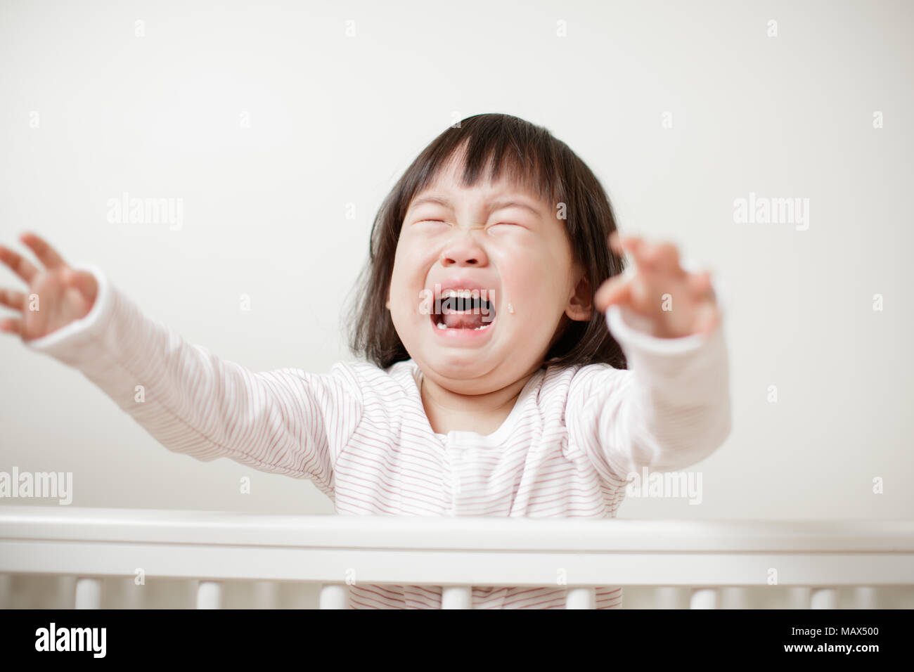 Crying Baby girl in cot bed Stock Photo