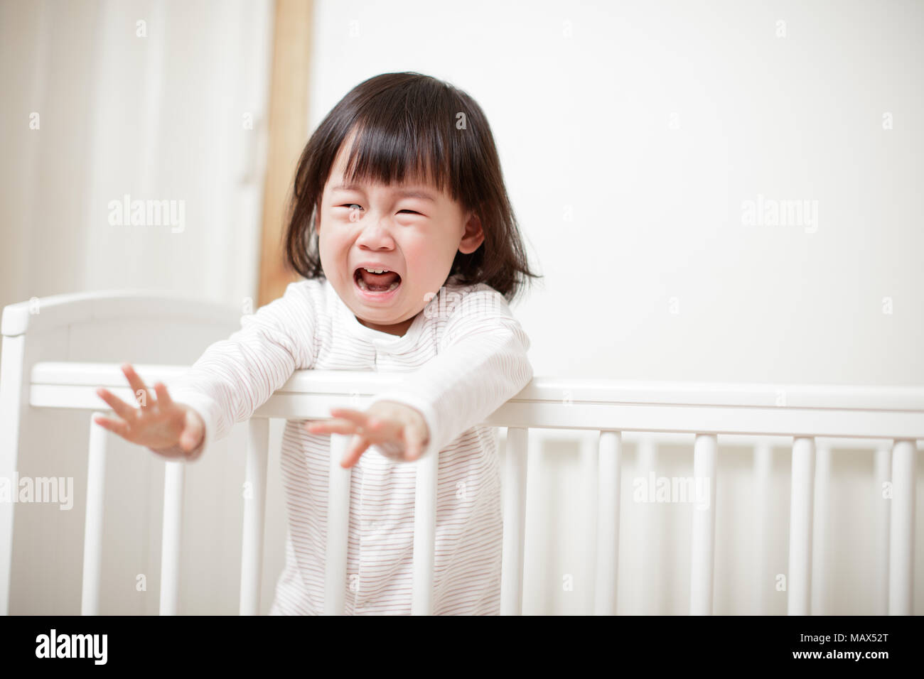Crying Baby girl in cot bed Stock Photo Alamy