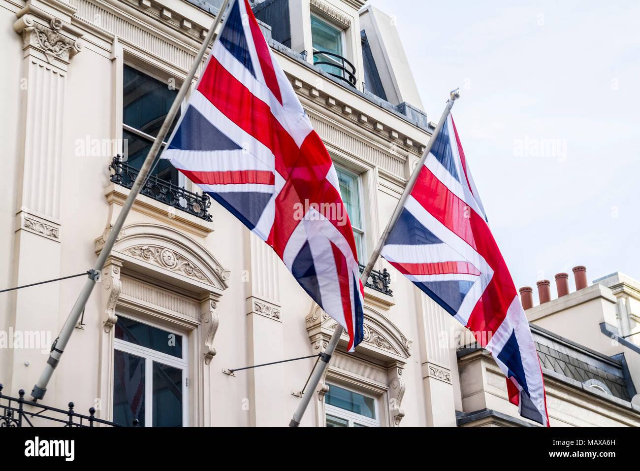 Two british flags, union jack flag, a pair of great britain flags hanging from flagpole, flagpoles, flying union jack London UK Stock Photo