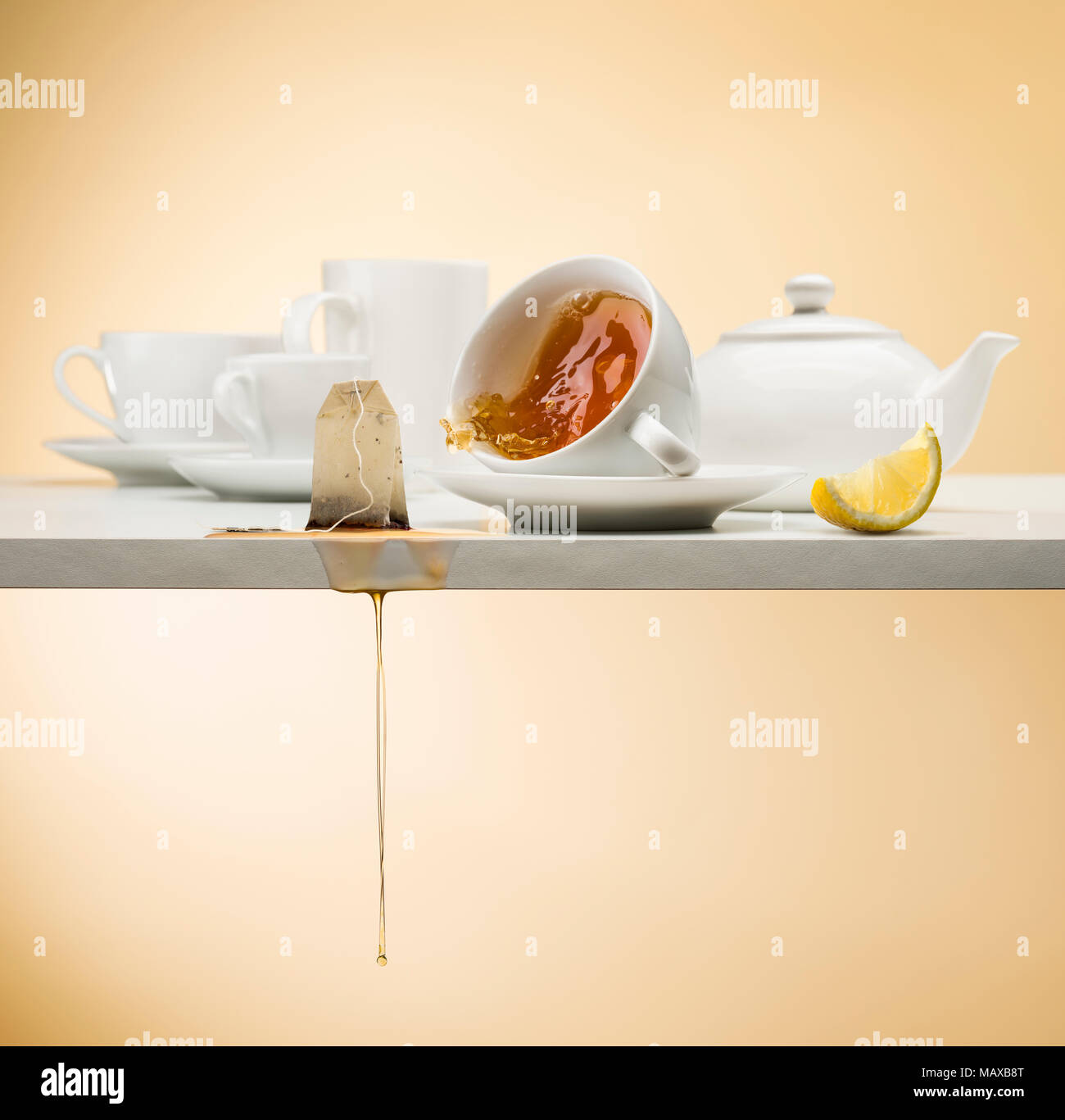falling cup of tea on white table with tea bag dripping and lemon slice Stock Photo