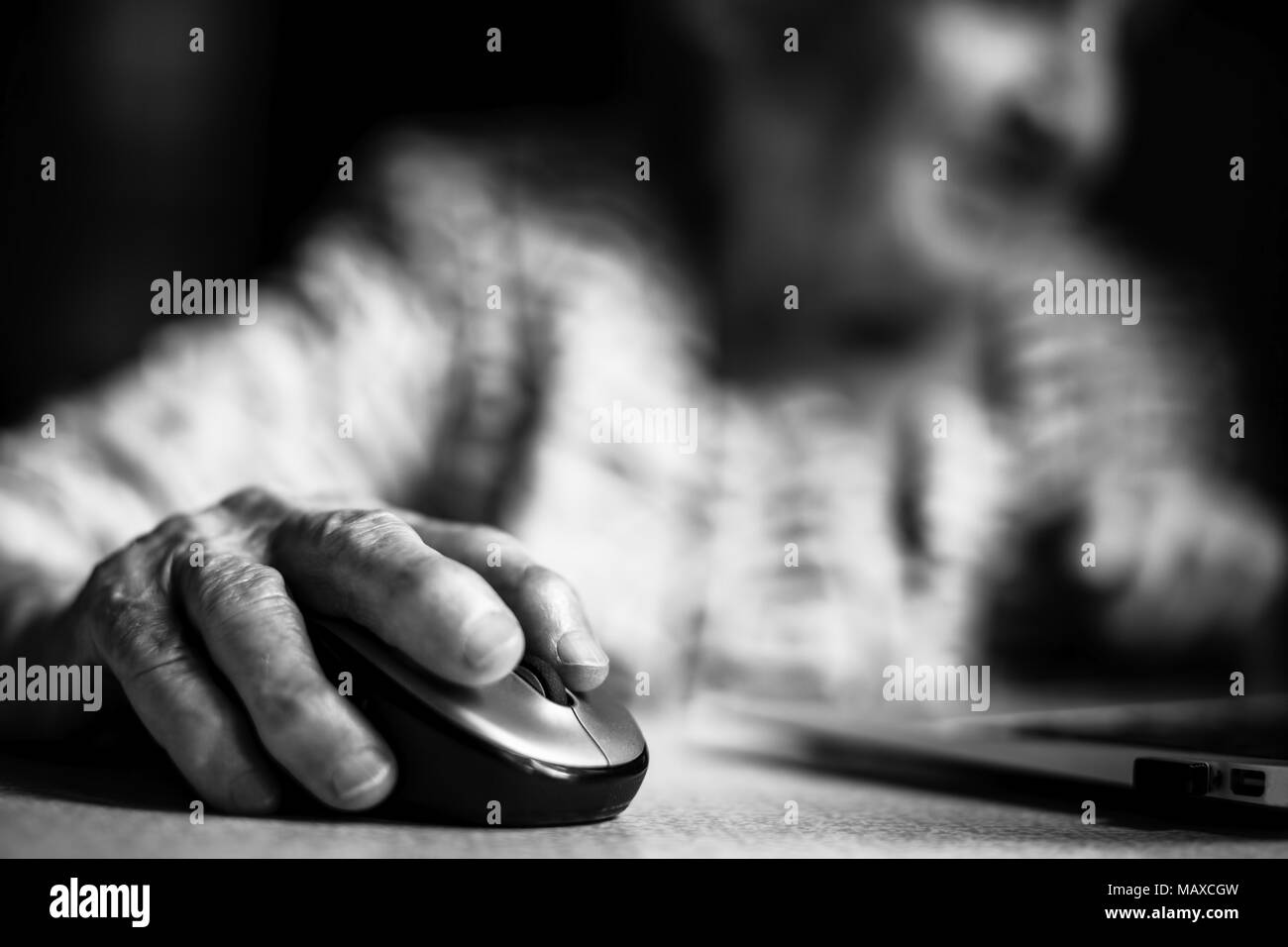 Hand of an elderly woman holding a computer mouse. Close-up. Stock Photo