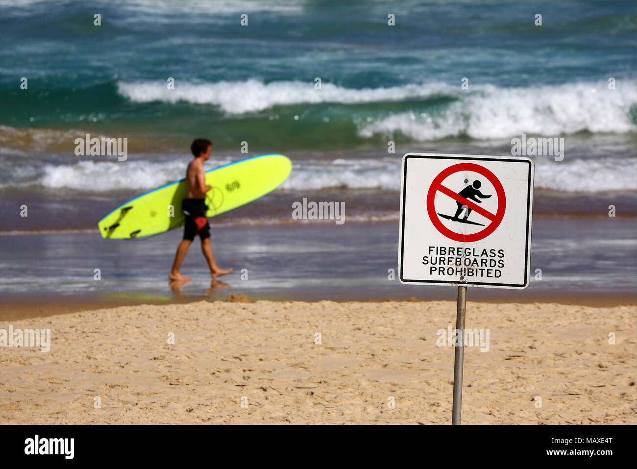Surfer with surfboard and no fibreglass surfboards sign on Bondi Beach, Sydney, New South Wales, Australia Stock Photo