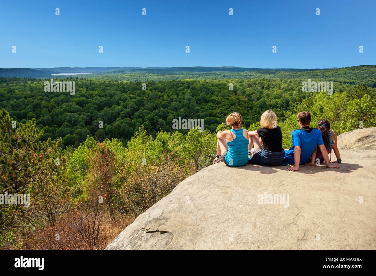 hikers sitting enjoying the view, Algonquin Provincial Park, Ontario, Canada The lookout area is a ledge of rock, 300-400 feet long, polished smooth b Stock Photo