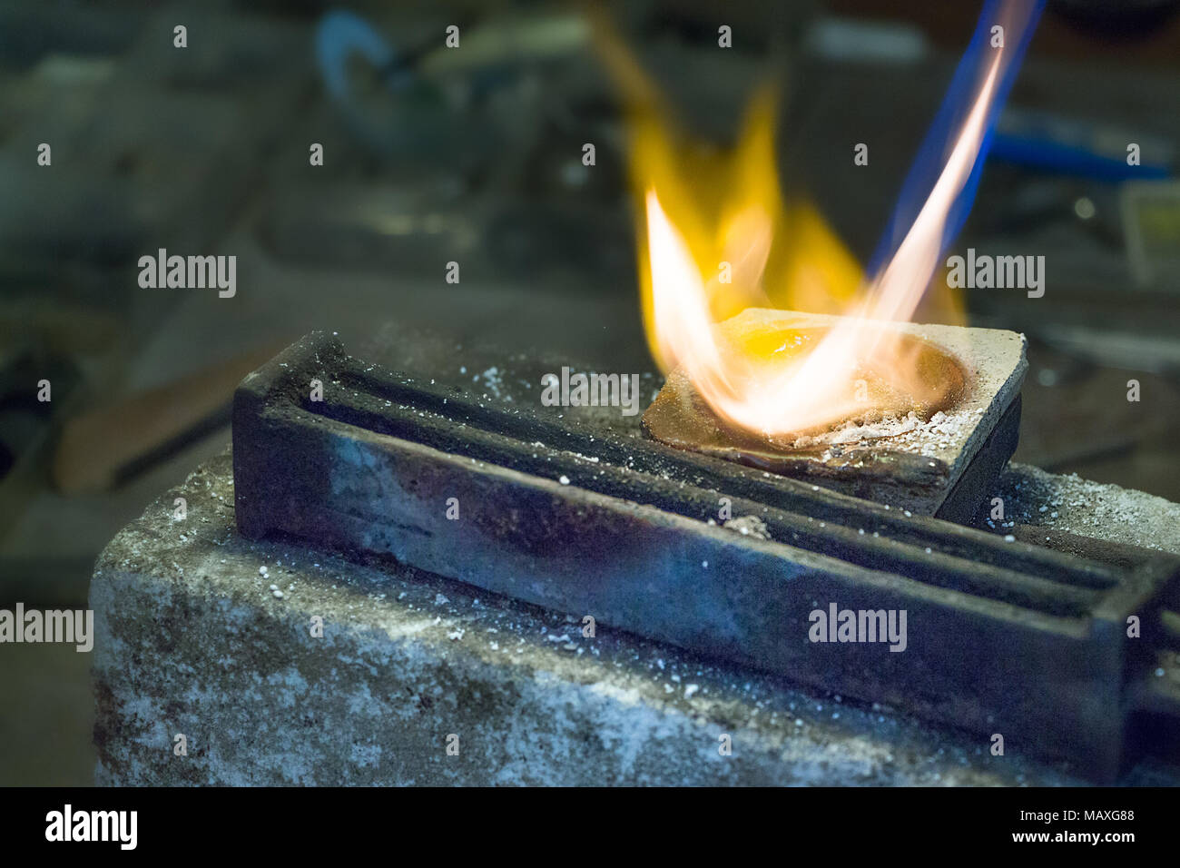 Jeweler melting silver on a ceramic melting pot with a gas torch and a