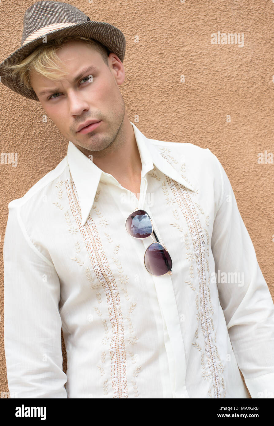 A Caucasian man, male model posing wearing men's 70s vintage shirt and hat, a men's vintage fashion editorial concept. Stock Photo