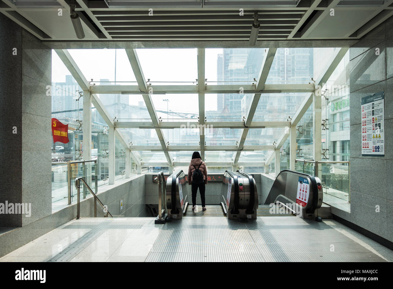 Girl Standing Alone Looking Out Window of Urban Subway Station Descending Elevator in Xi'an, China, 2018 Stock Photo