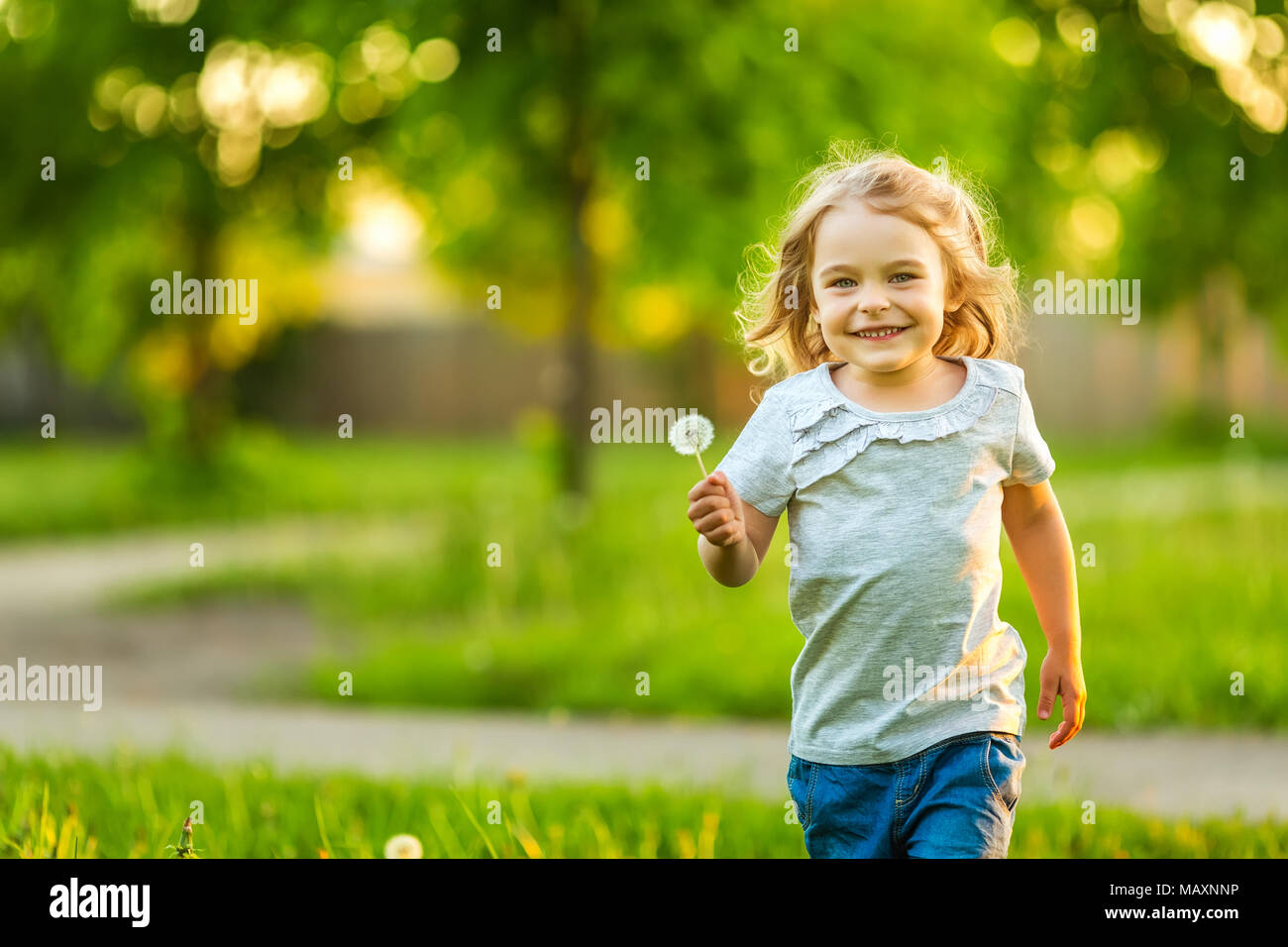 Little girl playing with dandelions in sunny park Stock Photo - Alamy