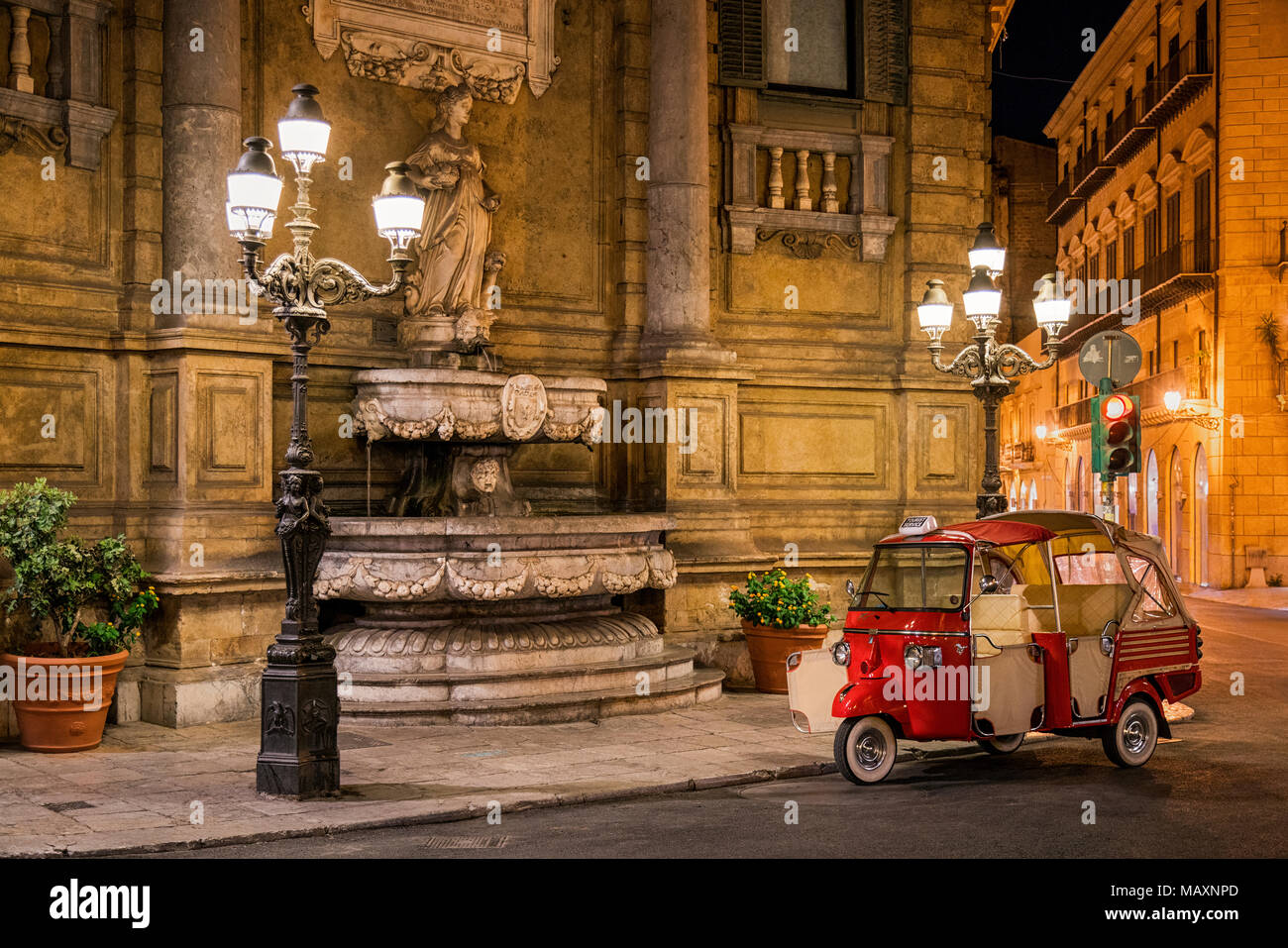 Quattro Canti in Palermo Sicily at night with a red 3 wheeled taxi parked on the corner, of the four fountains this is the north-east one with the sta Stock Photo