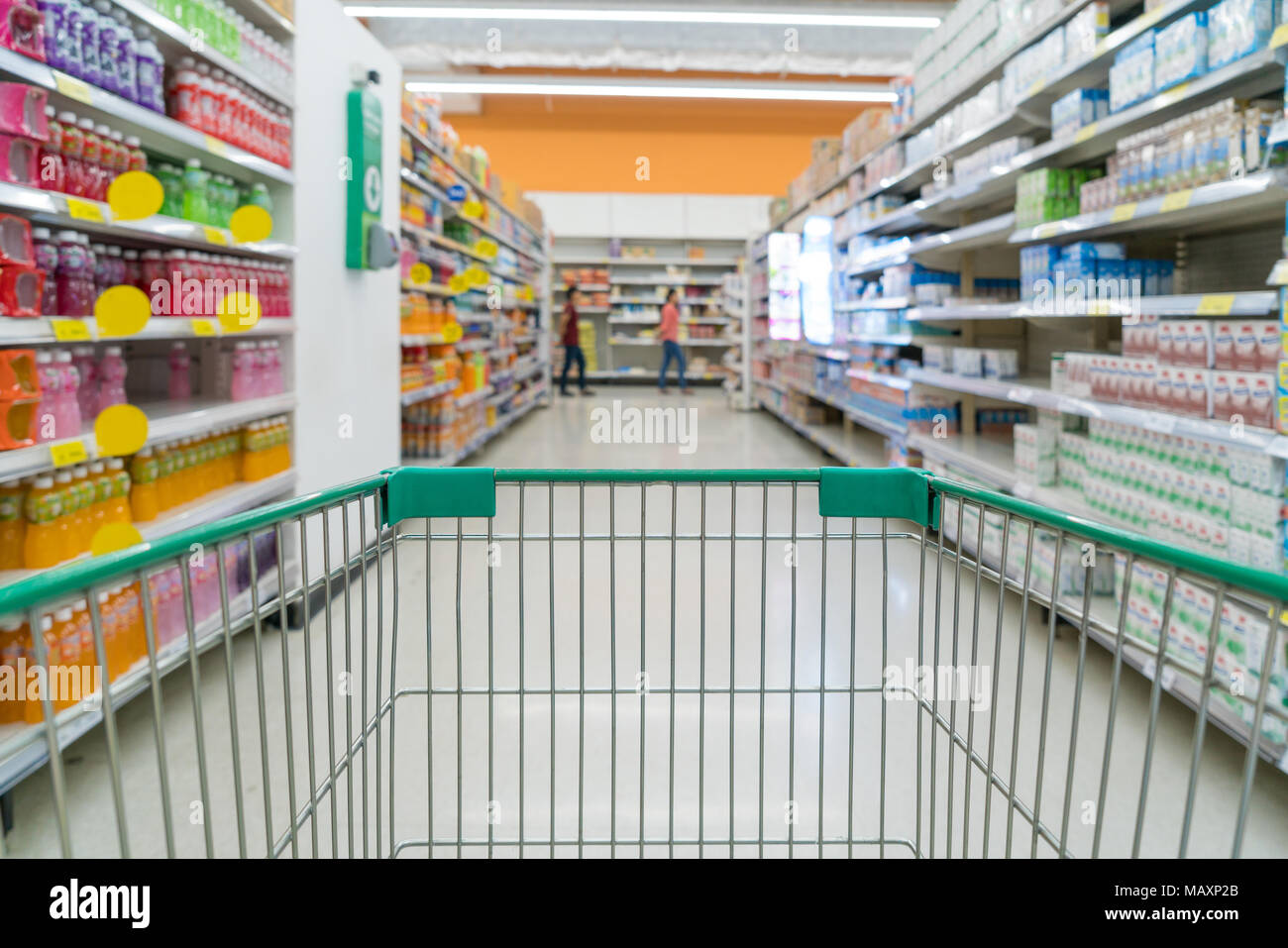 Abstract blurred photo of store with trolley in department store bokeh background. Supermarket aisle with empty green shopping cart Stock Photo
