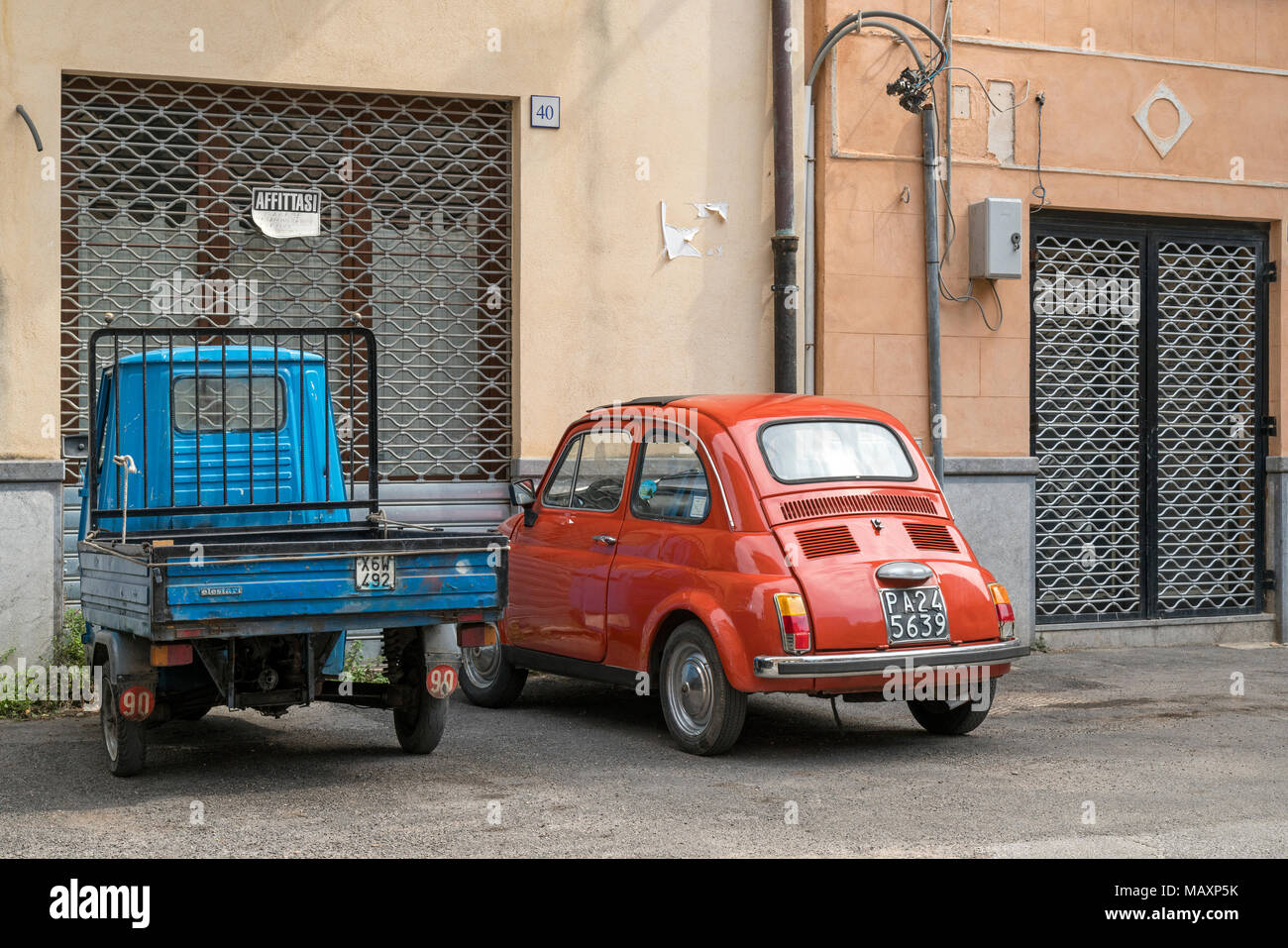 An old Piaggio Ape and Fiat 500 outside a building in Sicily with a sign saying 'Garage for Rent' Stock Photo