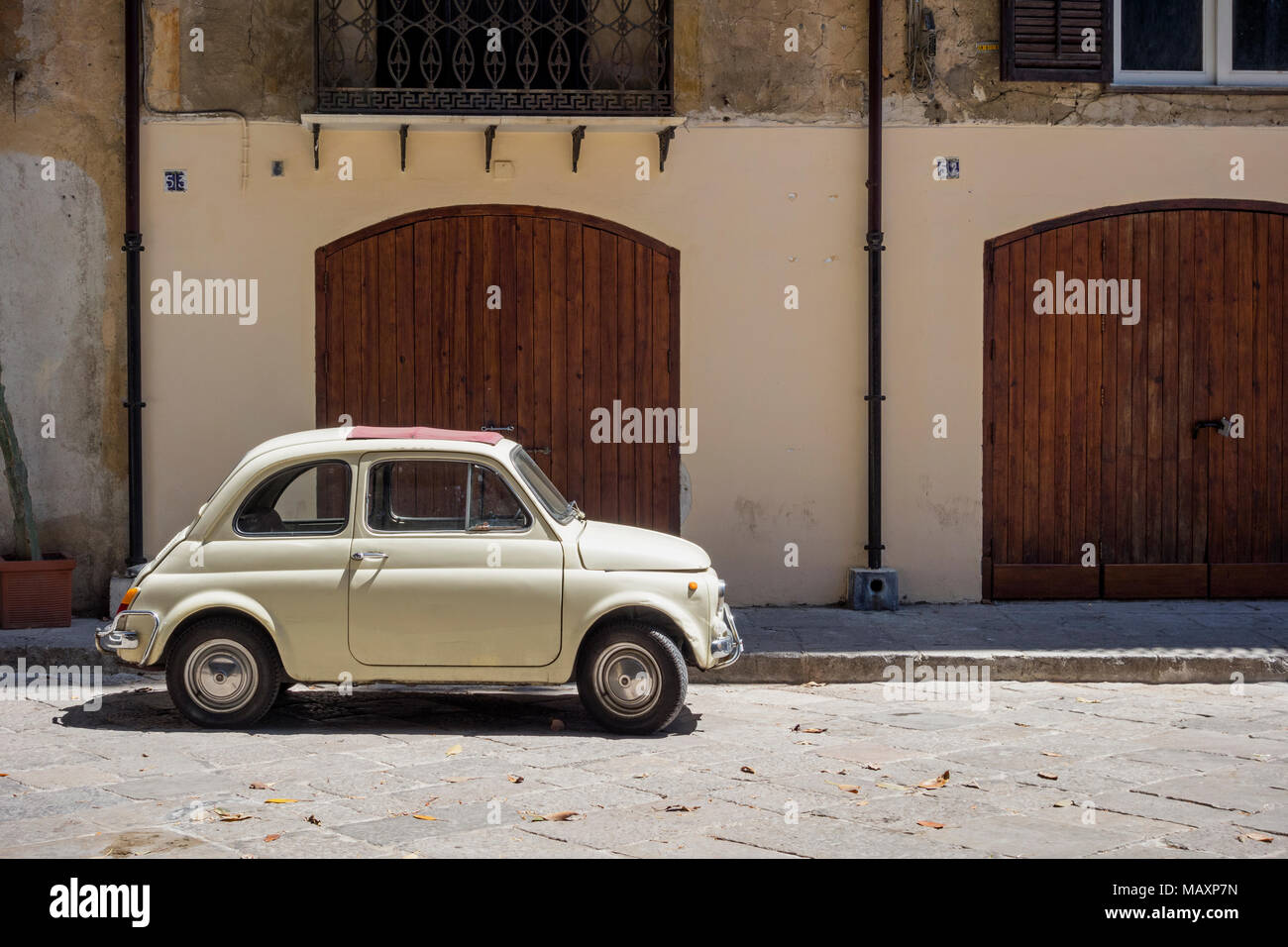 An old cream coloured Fiat 500 with red sunroof, parked outside a building in Palermo, Sicily. Stock Photo