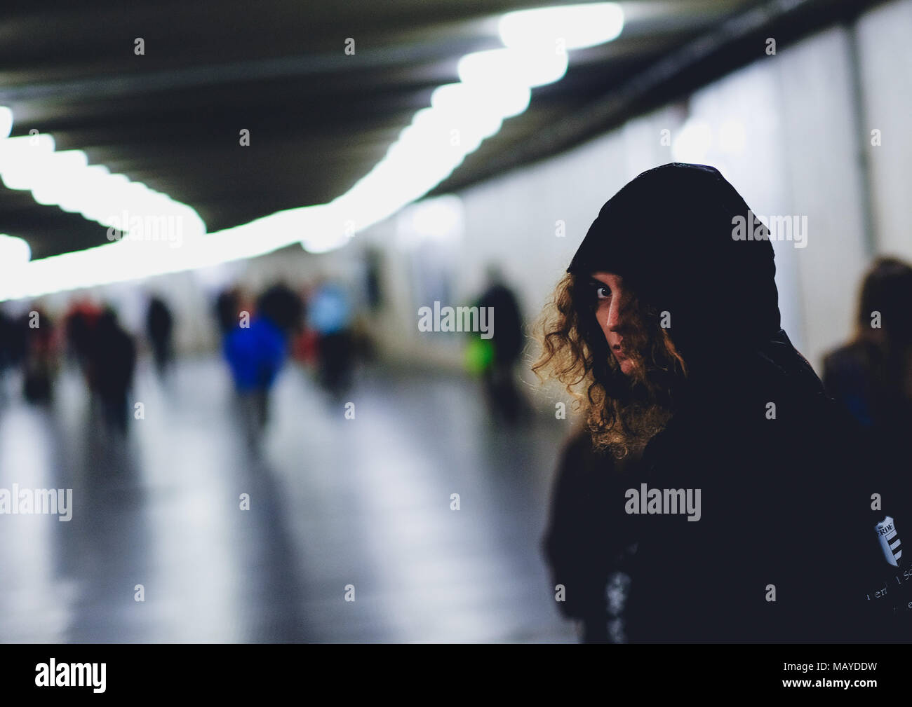 Girl being followed looking back in an underground passage Stock Photo