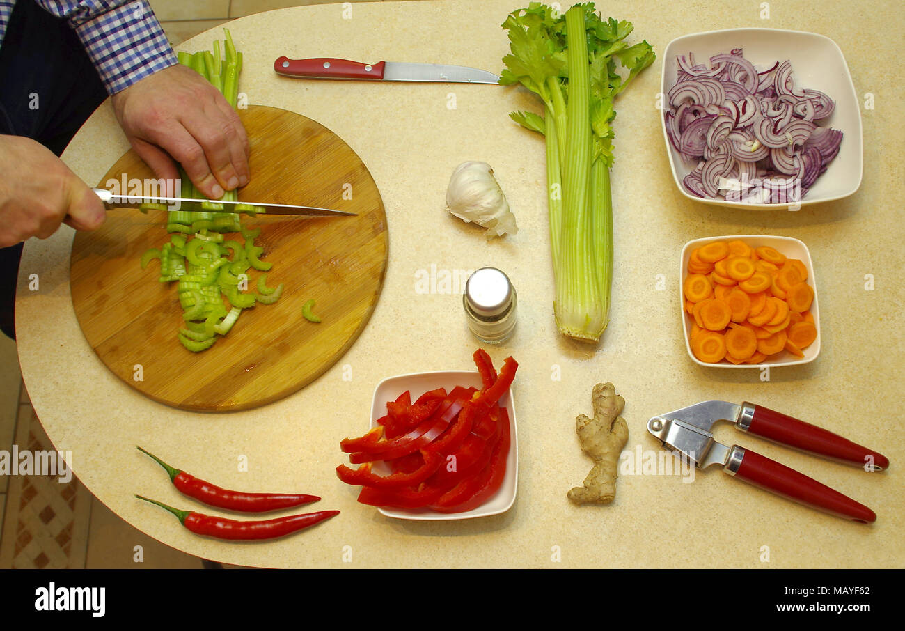 Vegetarian food cutting and preparing by man. View from top for board with vegetable nutrition. Stock Photo