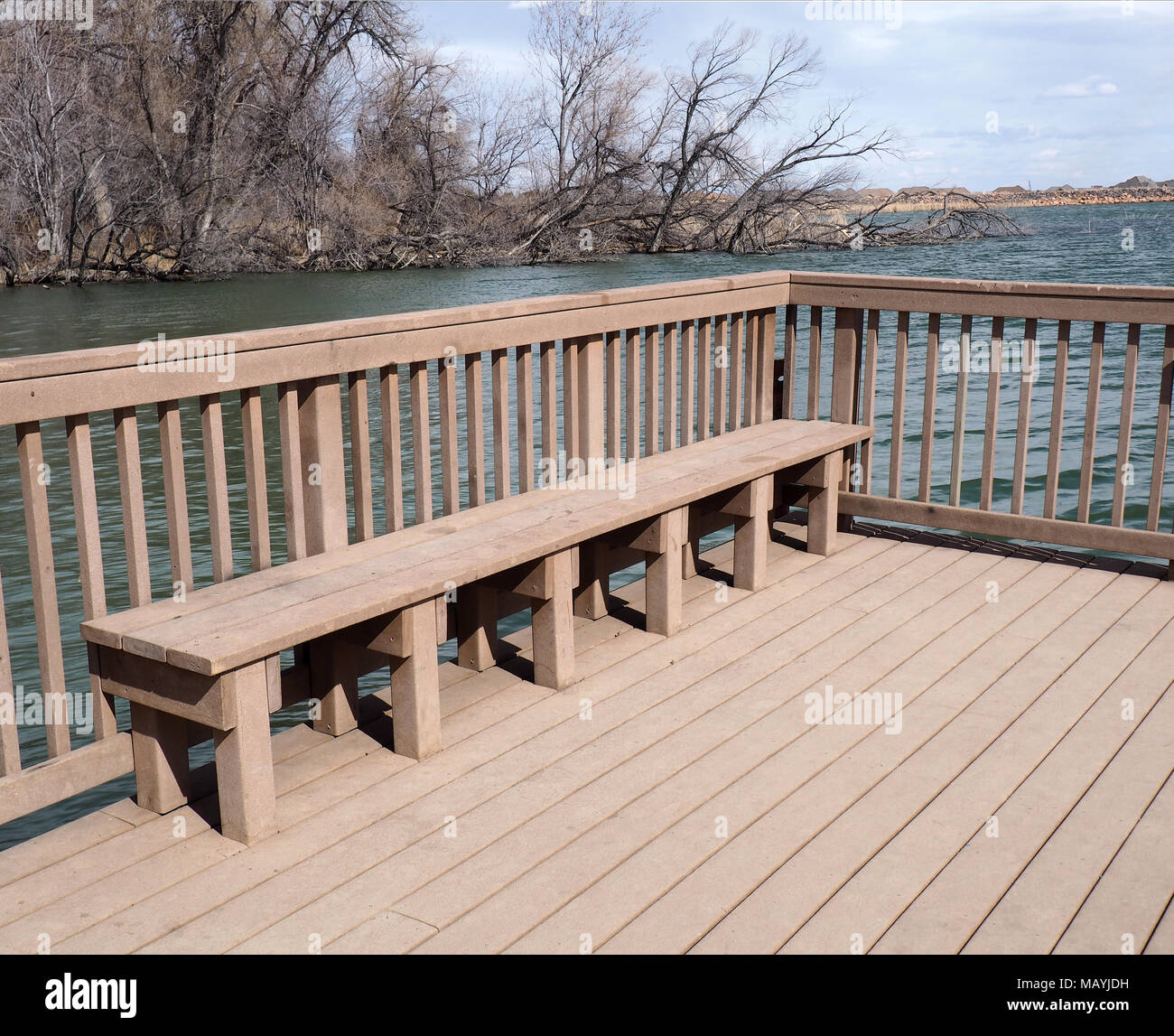 Bench made of composite material sits on a composite deck by a pond. Stock Photo