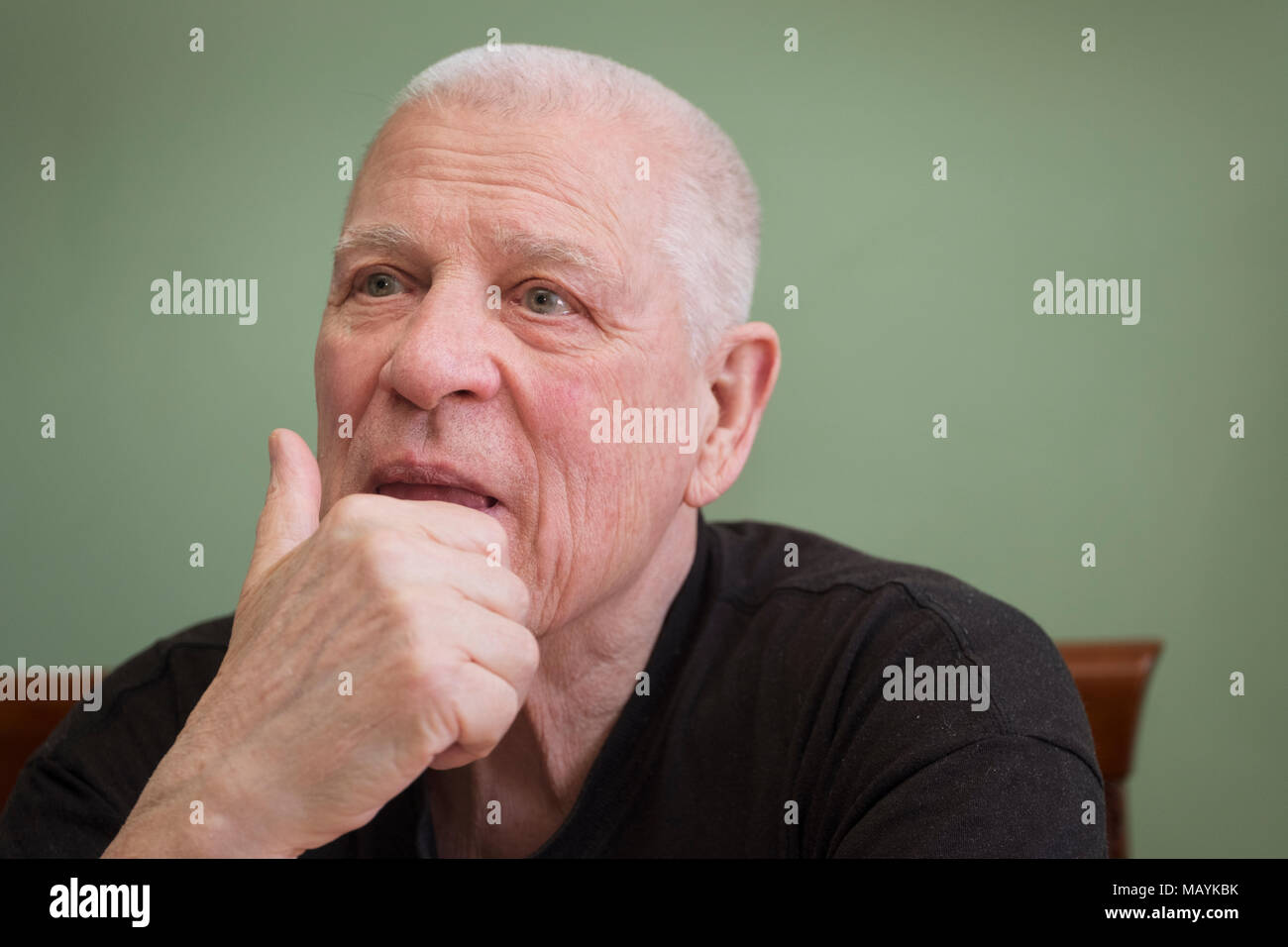 Dreamily or pensive looking senior man posing with a hand holding his head Stock Photo