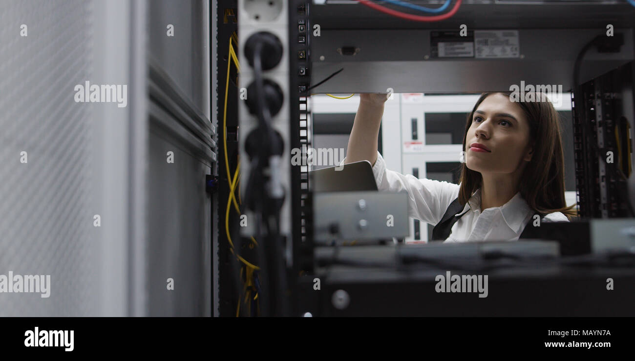 Technician performing maintenance tasks in a server room rack Stock Photo