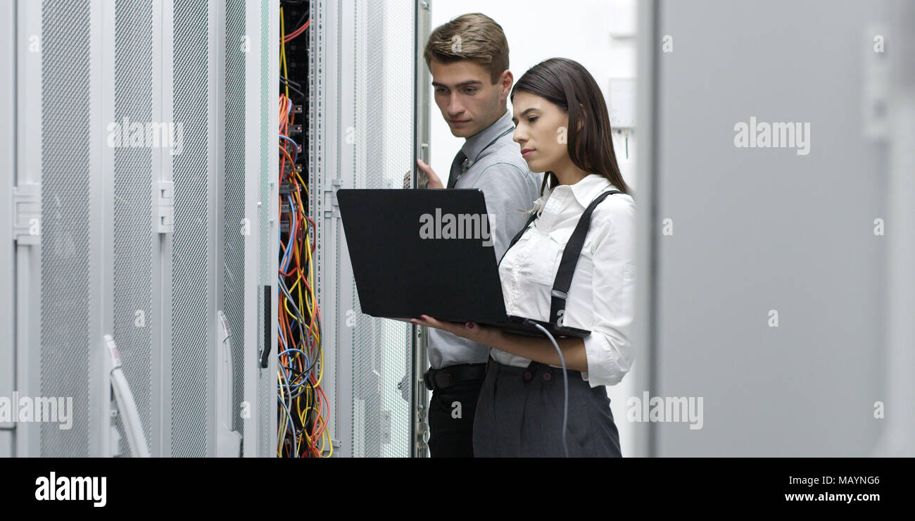 Technicians using laptop while analyzing server in server room Stock Photo