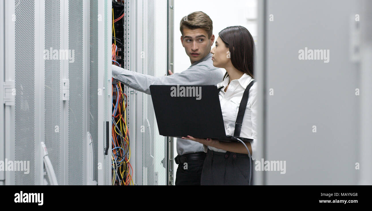 Technicians using laptop while analyzing server in server room Stock Photo