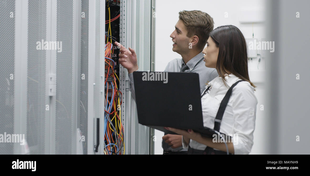 Technicians using laptop while analyzing server in server room Stock Photo