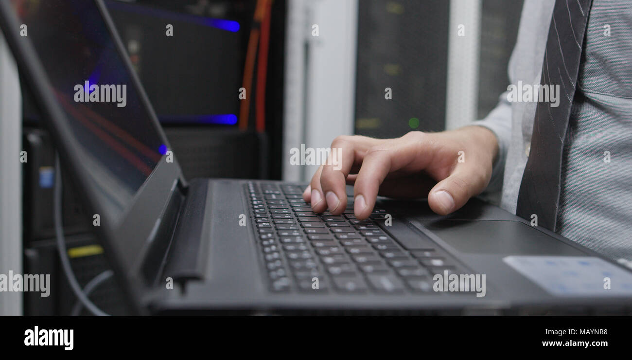 IT data specialist working on laptop on maintaining server rack Stock Photo
